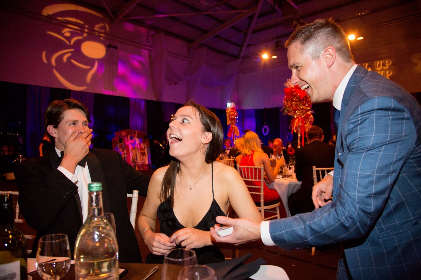 Guests laughing at close-up magic during a Manchester corporate dinner