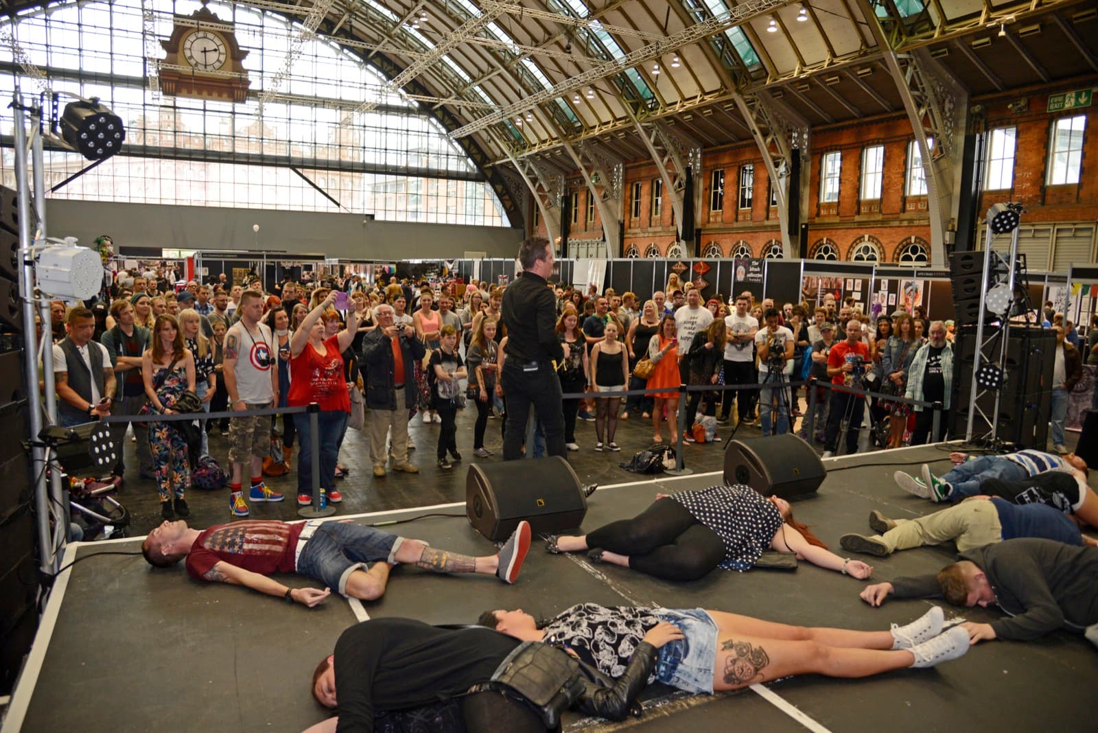 Stage hypnotist James Anthony with hypnotised volunteers lying asleep on stage in front of a large crowd