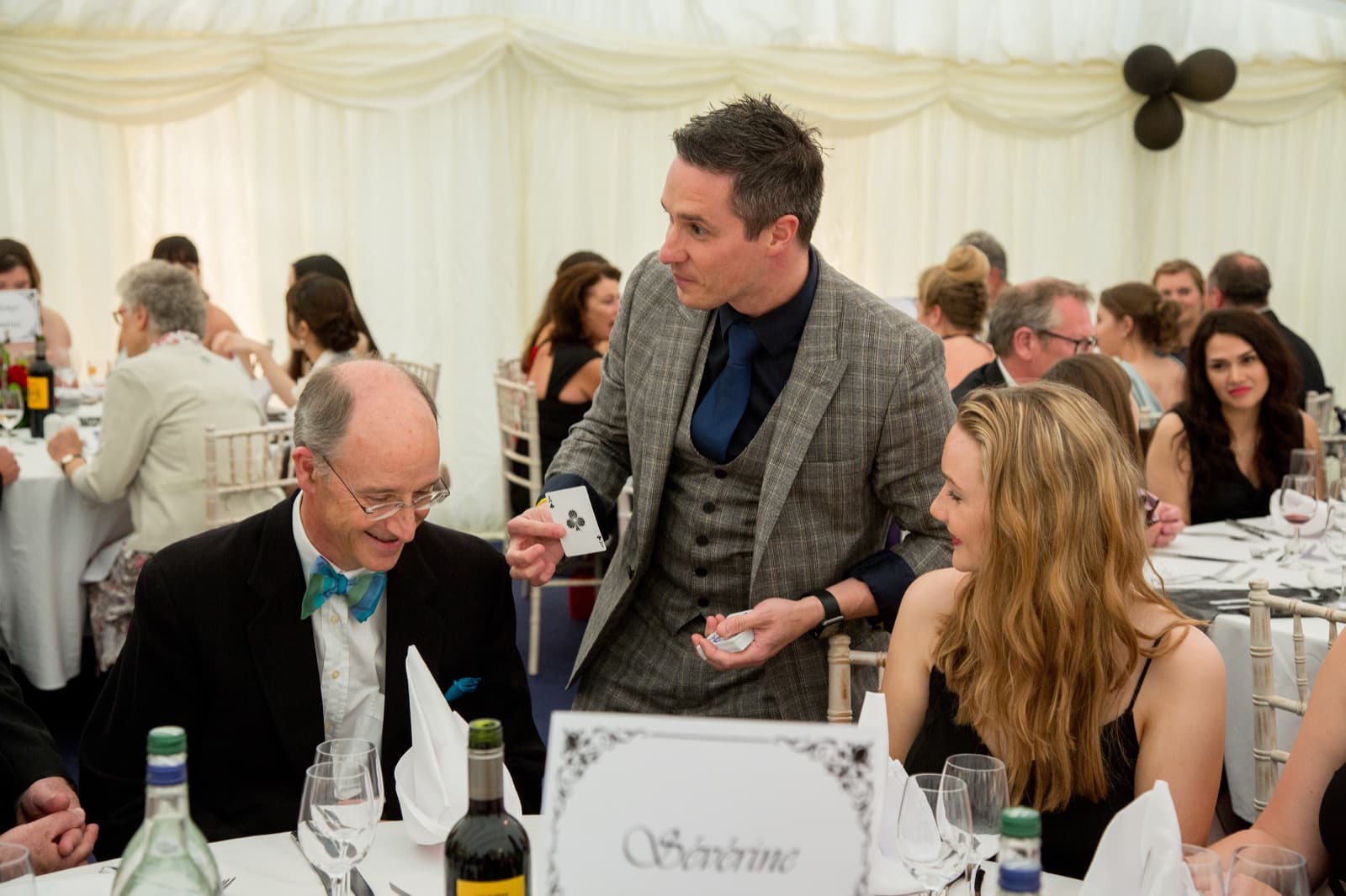 James Anthony performing magic at a table during a party in a marquee