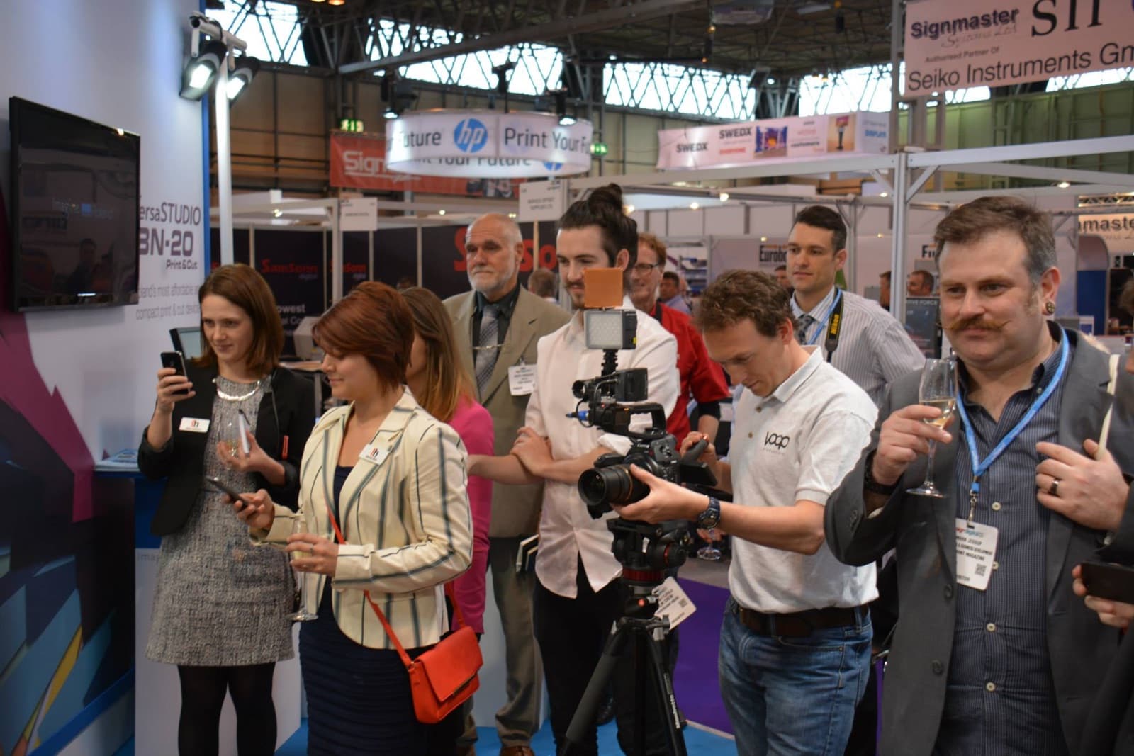 Crowd gathered at a trade show stand to watch James Anthony perform