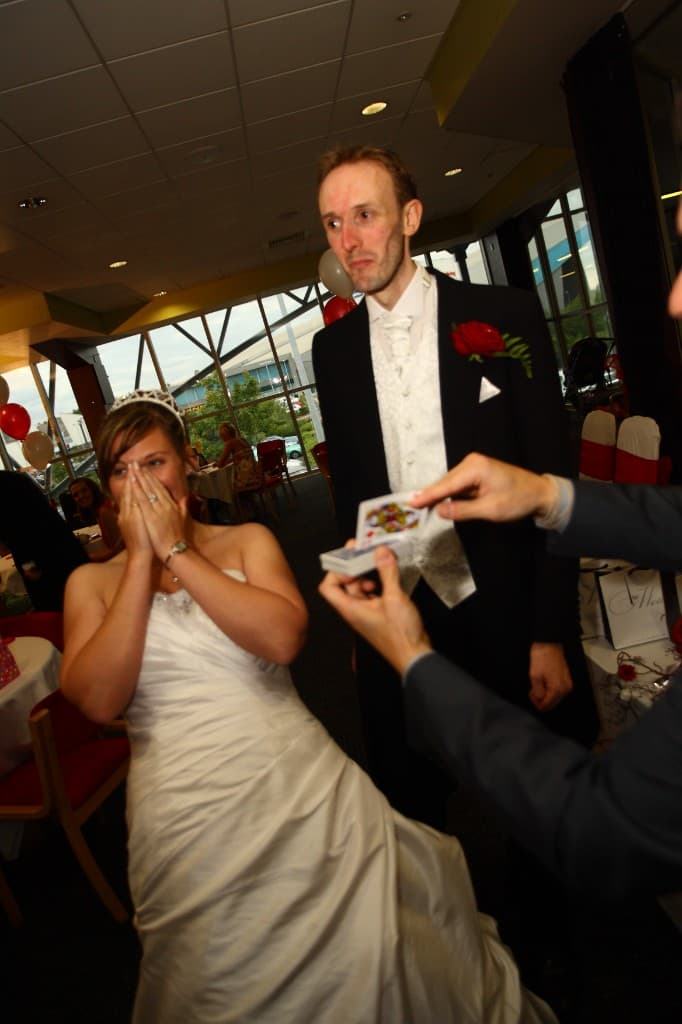 A bride with her hands over her mouth as James Anthony reveals her chosen card